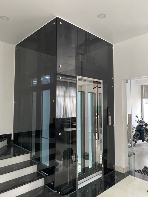 Thang máy gia đình khung thép vách kính đen khung bao bản rộng vuông