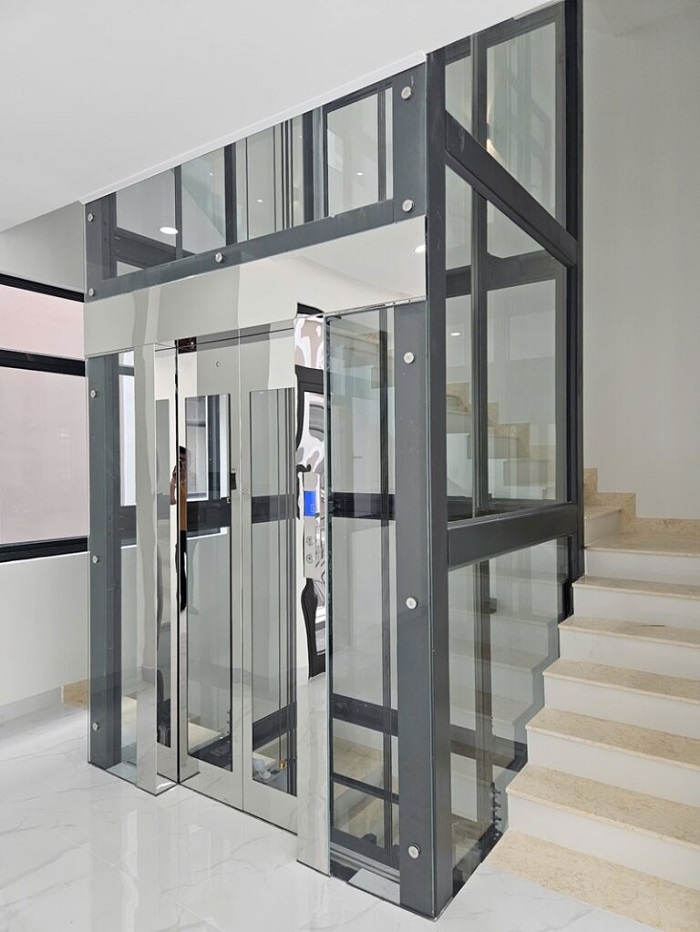 Thang máy khung thép sơn tĩnh điện đen vách kính cửa inox trắng gương khung bao bản rộng