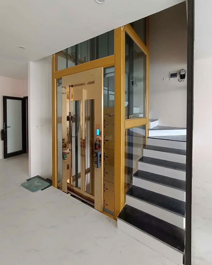 Thang máy kính homelift khung sơn tĩnh điện vàng cửa inox vàng gương khung bao bản rộng