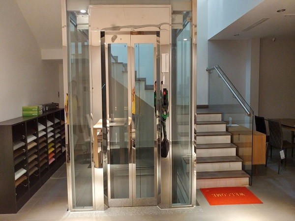 Thang máy buồng kính khung thép ốp inox trắng gương